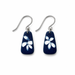 A pair of silver-tone dangle earrings with dark navy blue teardrop-shaped charms featuring a white hand-painted flower motif, shown on a plain white background.