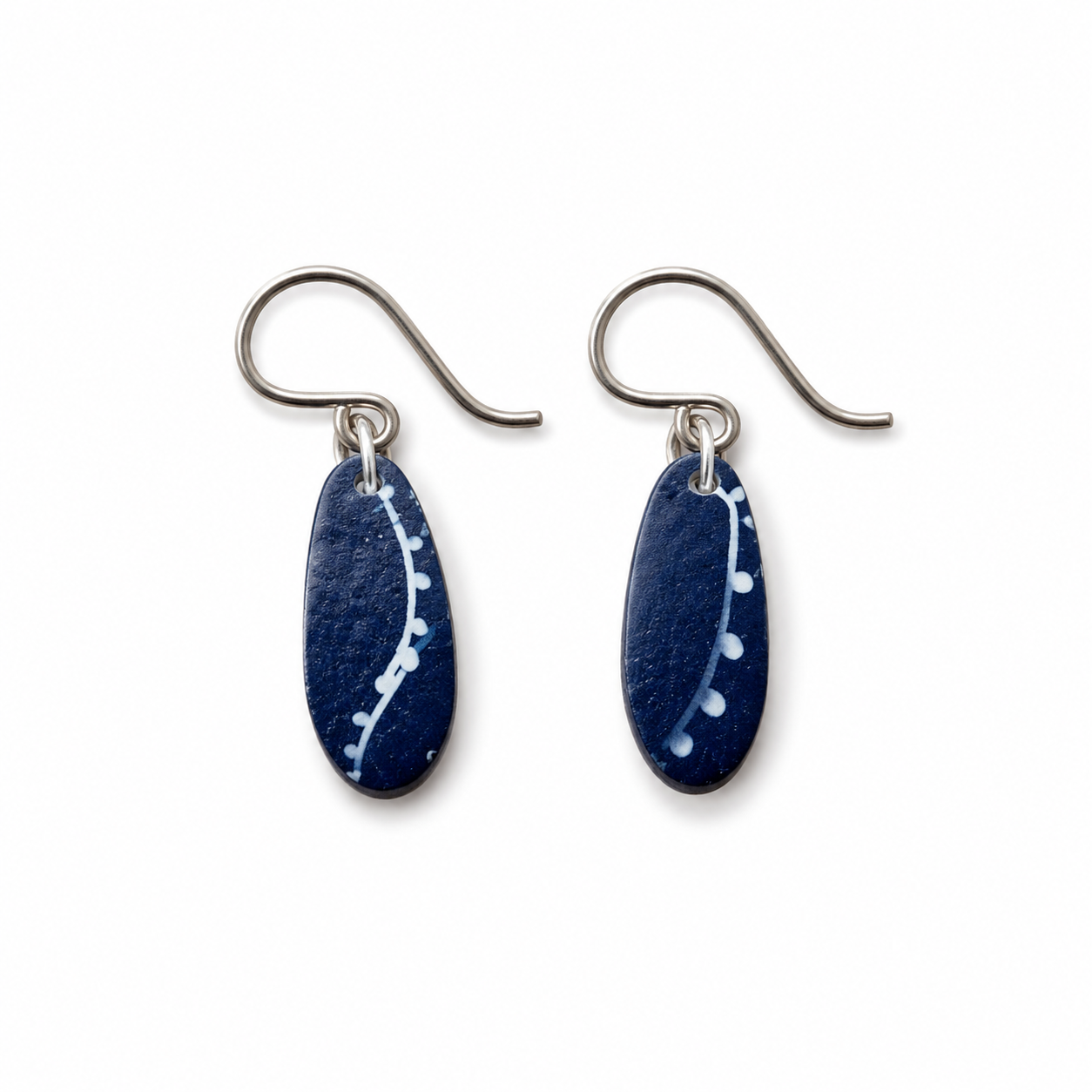 A pair of handmade dangle earrings featuring dark blue teardrop-shaped glass pendants with white speckled patterns, suspended from silver-tone fishhook wires, shown on a plain white background.
