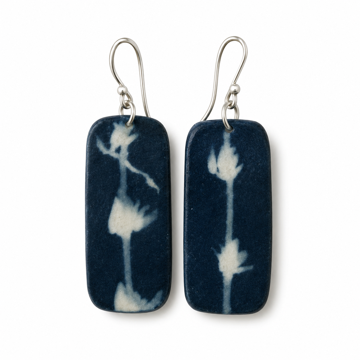 A pair of rectangular dark blue and white shibori tie-dye ceramic drop earrings with silver fishhook ear wires, shown against a plain white background.