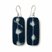 A pair of rectangular dark blue and white shibori tie-dye ceramic drop earrings with silver fishhook ear wires, shown against a plain white background.