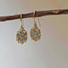 Gold clustered earrings with blue stones hanging on a branch