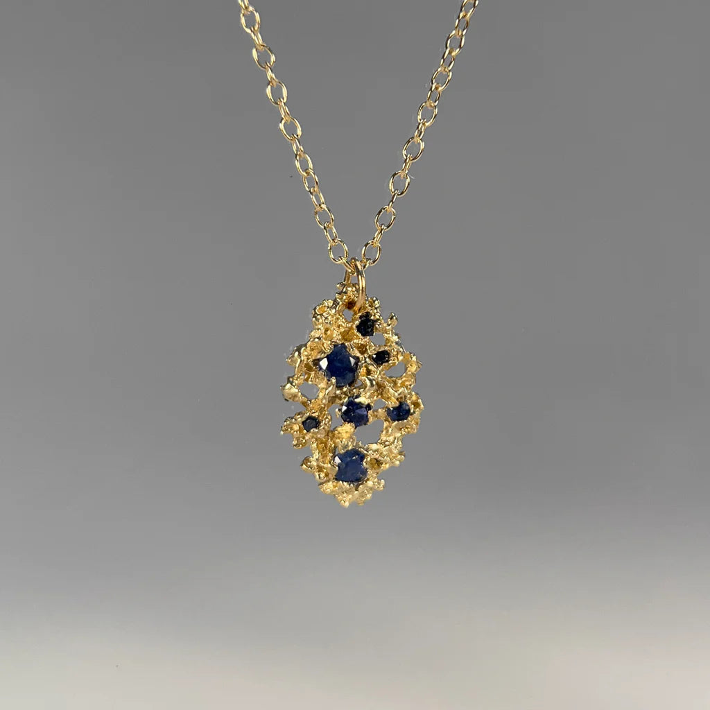 Gold necklace with gold clustered pendant featuring blue stones 