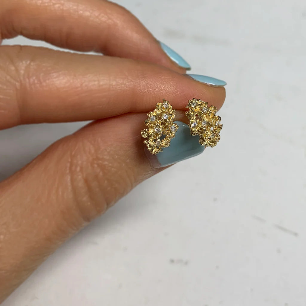 Gold clustered earrings held between fingers 