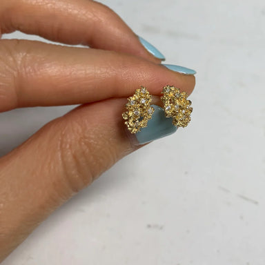 Gold clustered earrings held between fingers 