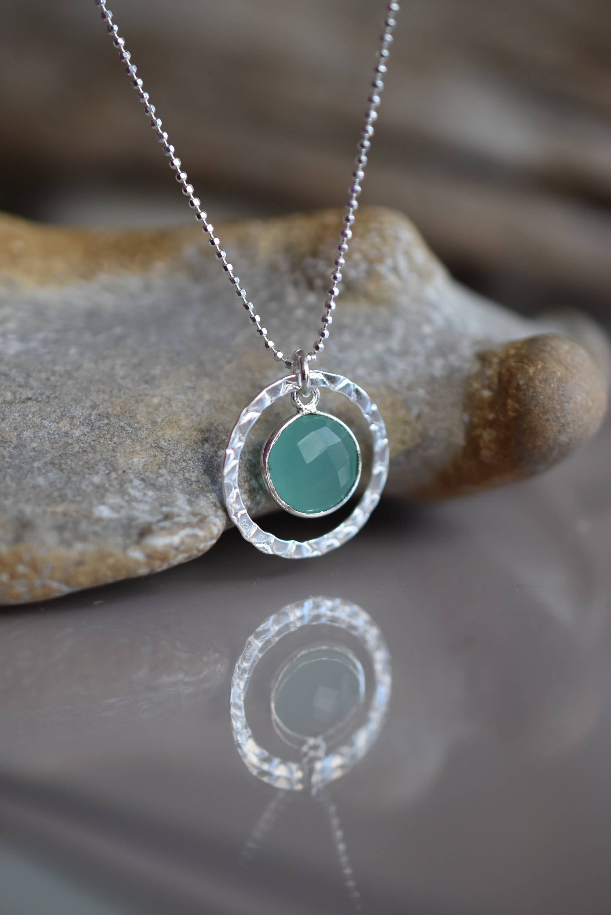 Close-up of the Sterling Silver Aqua Chalcedony Necklace by Whitelotus Design, showcasing the beautiful aqua chalcedony gemstone set in a hand-textured circular bezel, reflecting light elegantly.