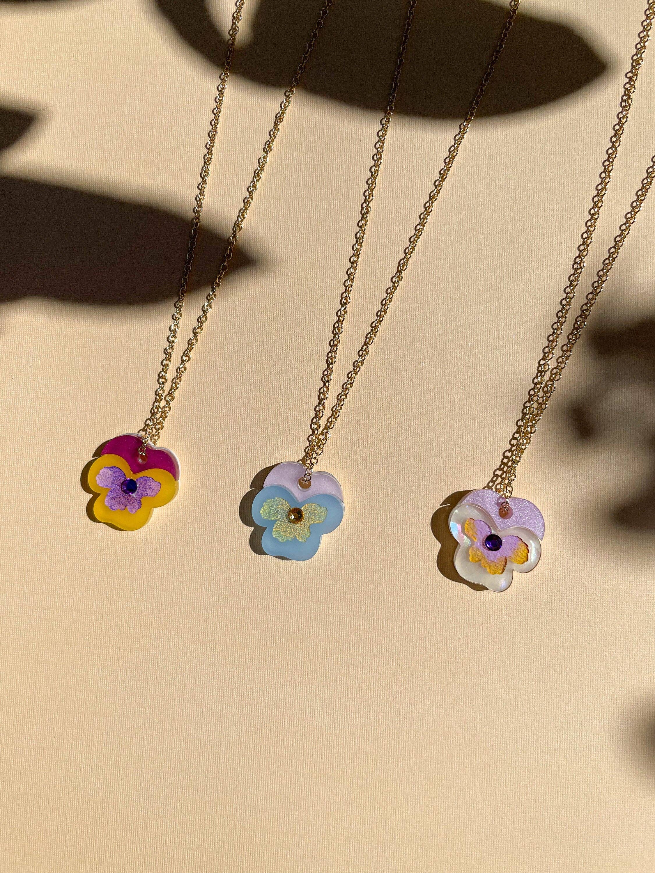 Three colorful Mini Pansy Necklaces by Sunnie Creative showcasing unique floral designs made of acrylic with stainless steel chains.