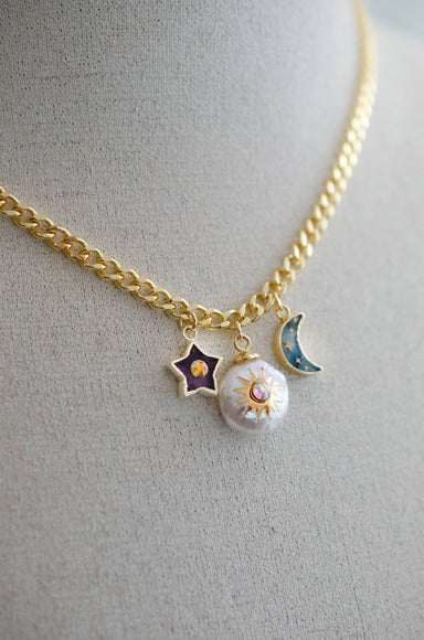 Close-up of the Pearl and Moon Celestial Charm Necklace by Jill Makes, featuring gold-detailed charms inspired by the night sky including an amethyst star, pearl sun, and labradorite moon on a gold curb chain.