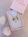Elegant presentation of the Pearl and Moon Celestial Charm Necklace by Jill Makes in a pink box, featuring gold charms of a pearl sun, amethyst star, and labradorite moon, surrounded by crystals.