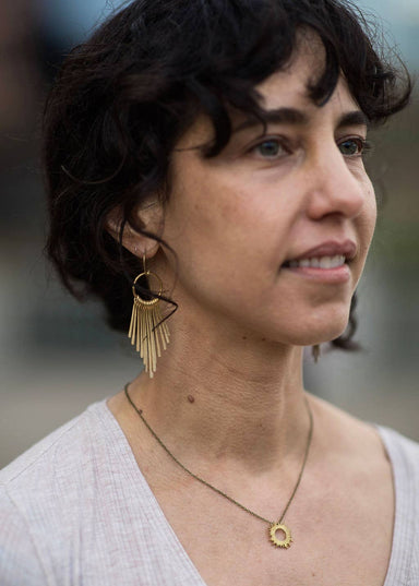 woman wearing kinetic fringe earrings in brass