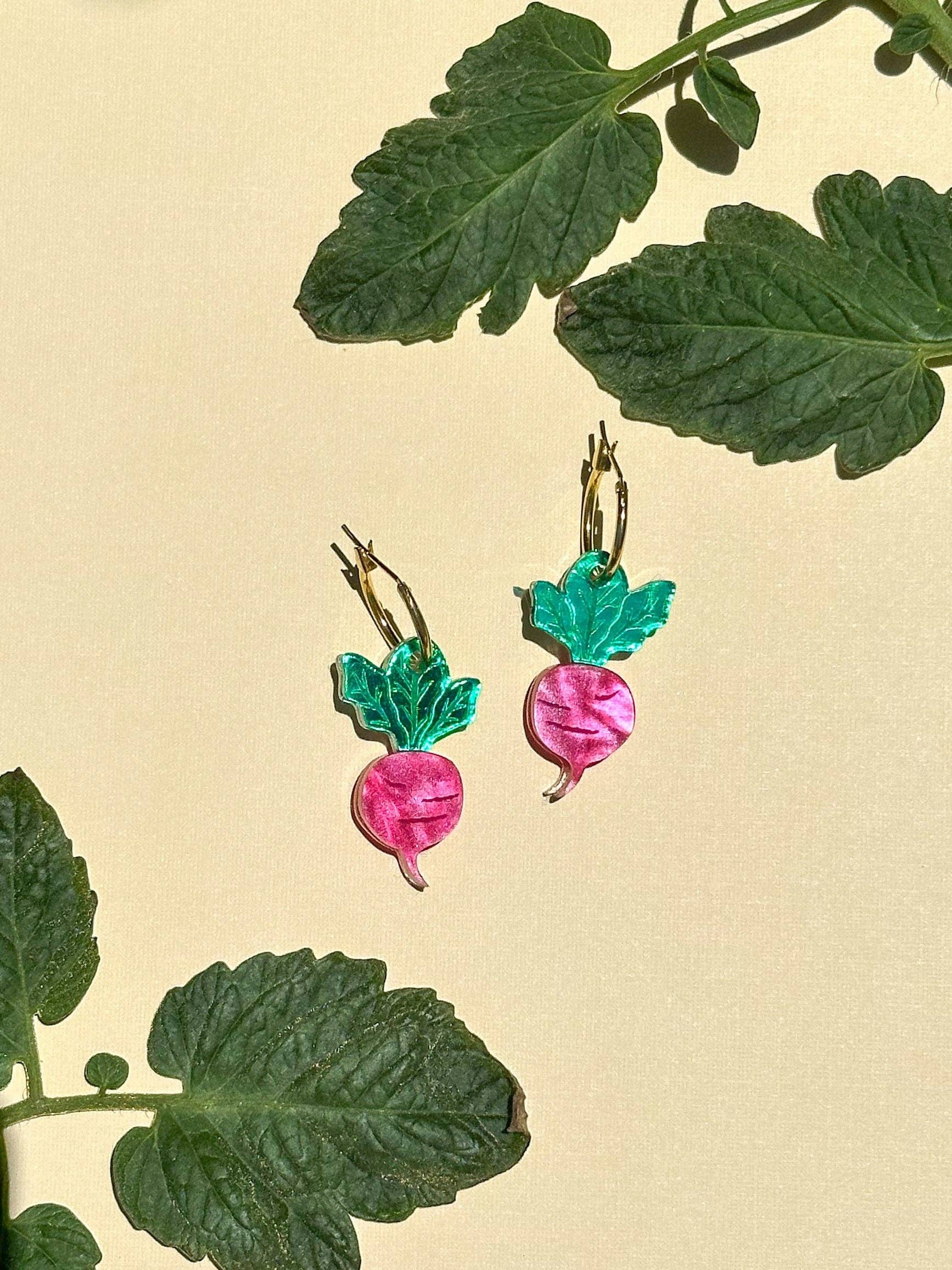 Colorful Mini Radish Dangle earrings by Sunnie Creative, featuring vibrant pink radish design with green leaves, set against a soft beige background.