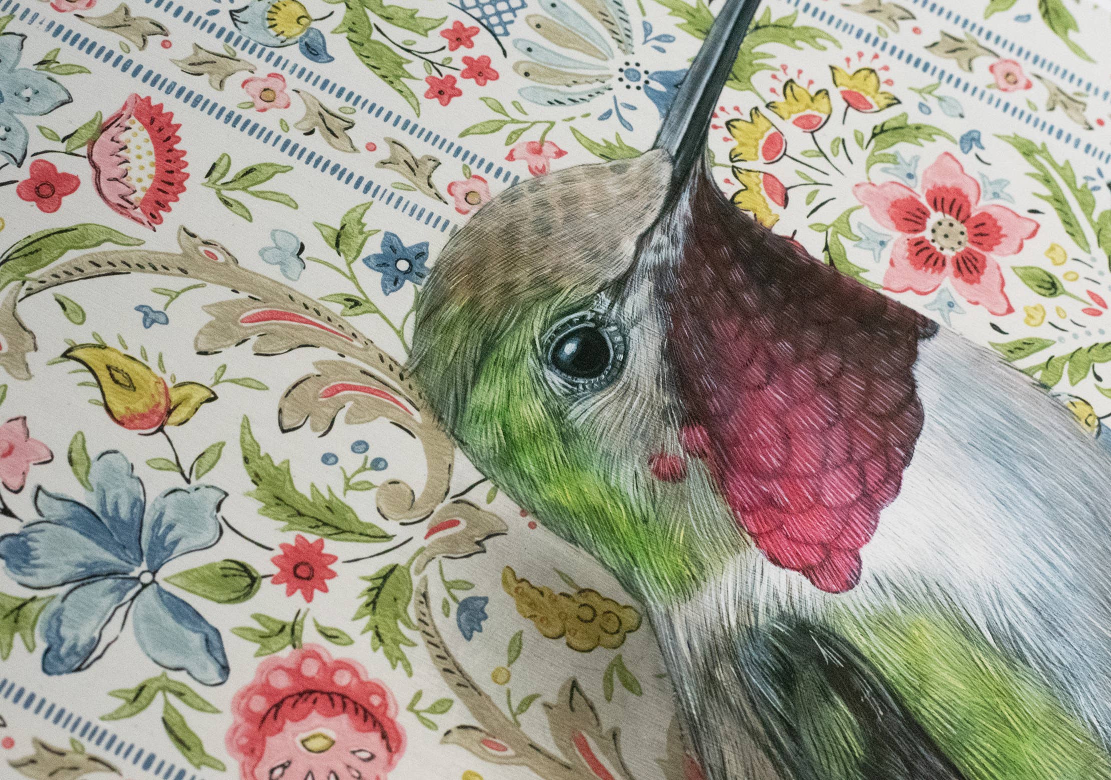 Framed art print of a hummingbird on a floral patterned background.