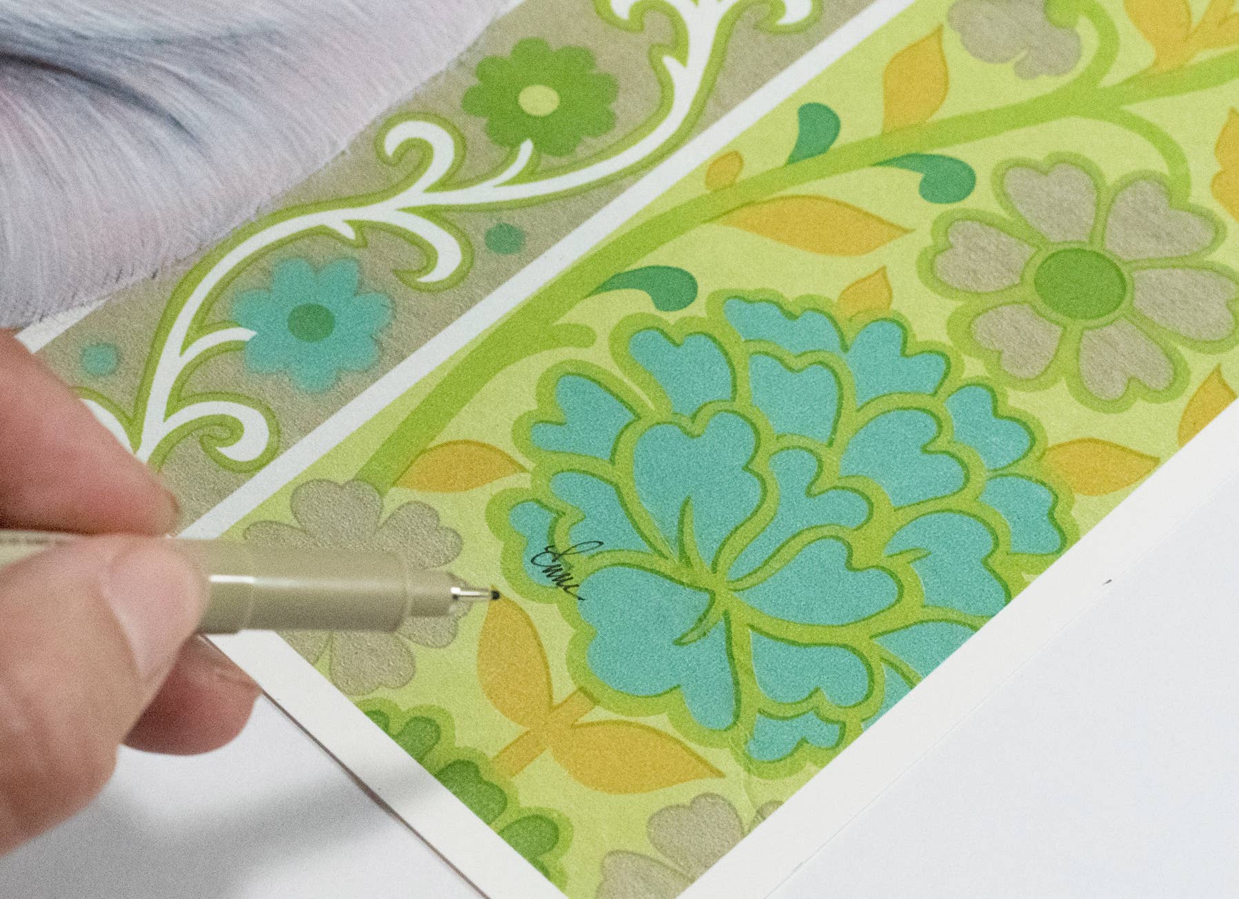 Emily Uchytil hand-signing a pig fine art print, showcasing the artist's dedication to their work alongside the colorful farm animal illustration.