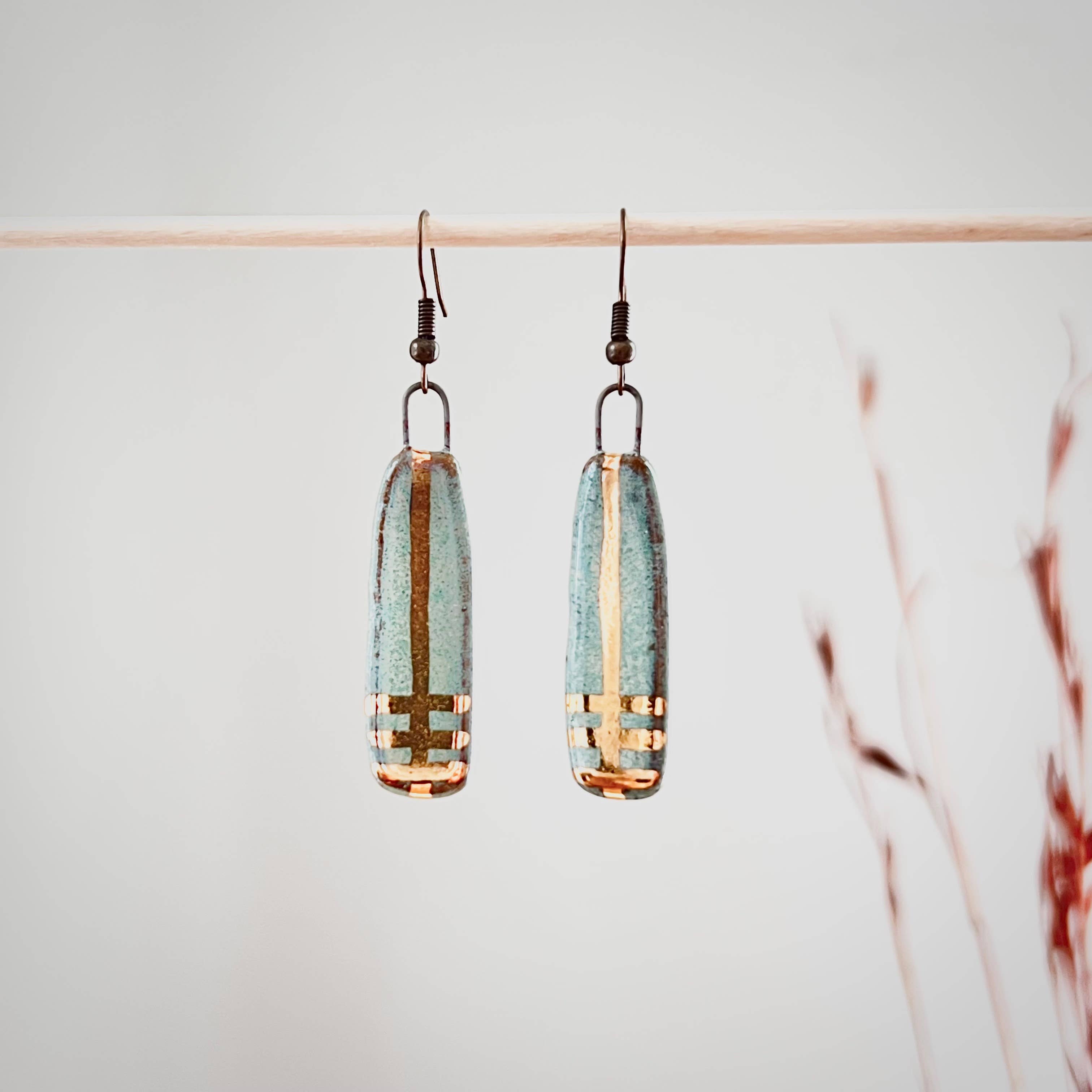 Turquoise Long Line Designed Earrings from The Artifact House displayed hanging, highlighting the unique handmade glazing and 24K gold detailing.