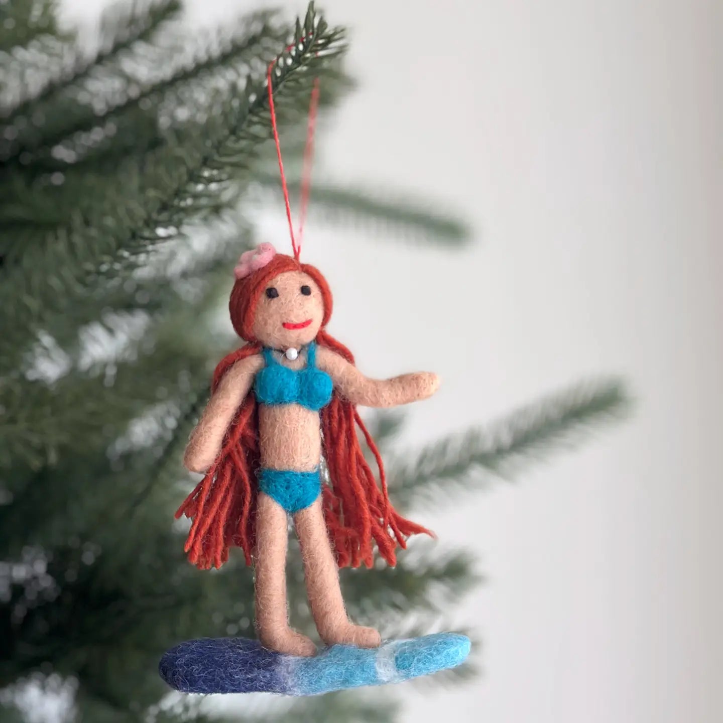 Felt Surfer Girl Ornament with red hair, featuring a flower on her head, perfect for bringing a playful summer spirit to your tree.