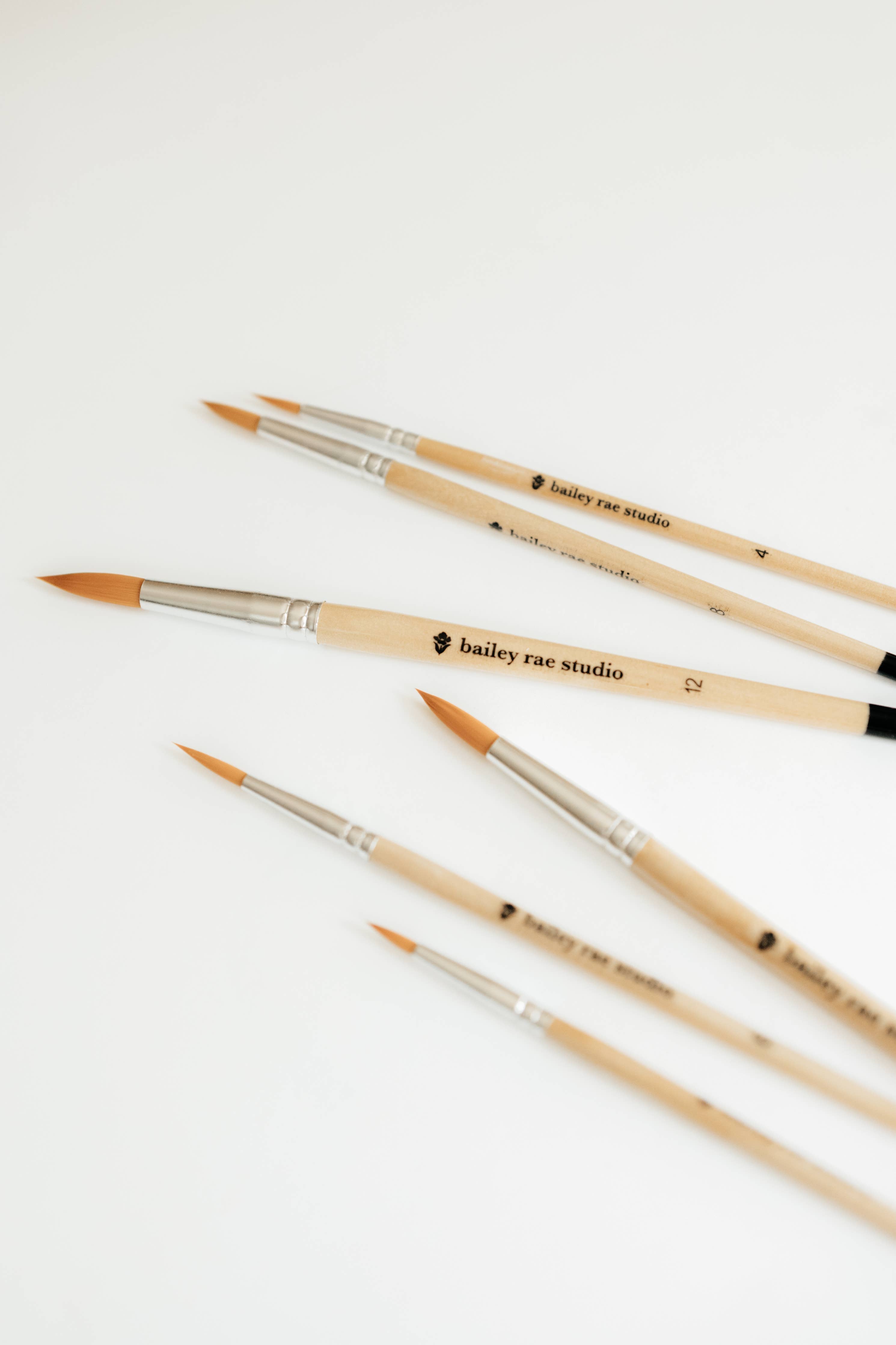 Artist using the Round Tip Watercolor Brush Set - 6 piece for delicate line work in their creative project.