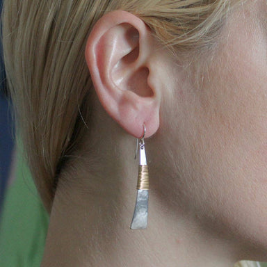 Long Wire Wrapped Triangle Wire Earring by Marjorie Baer, displayed on a model's ear, highlighting its elegant silhouette and artisan details in silver and brass.