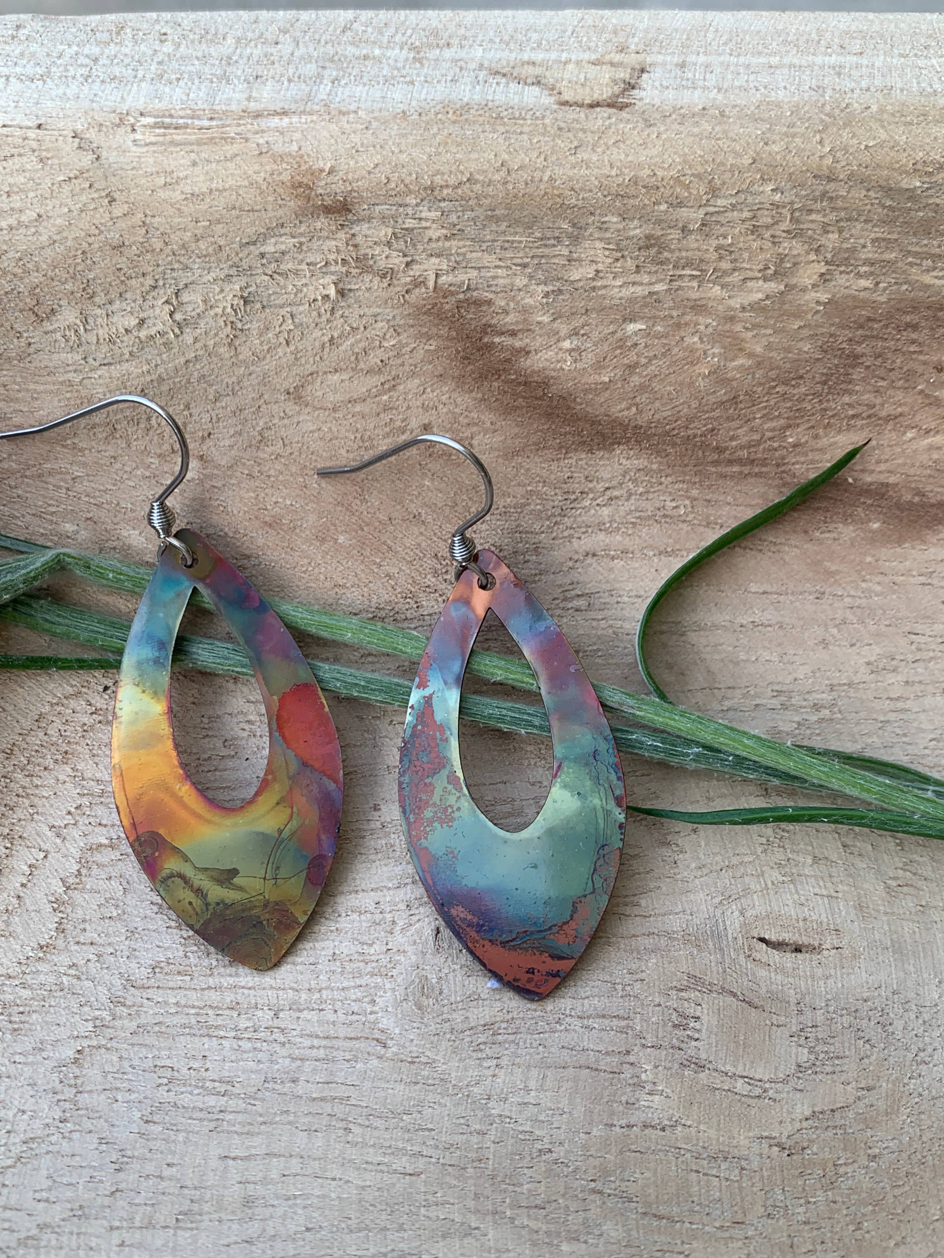 Close-up of Pointed Teardrop Fire Painted Copper Earrings hanging from stainless steel ear wires, featuring a lightweight design and fun colorful pattern.