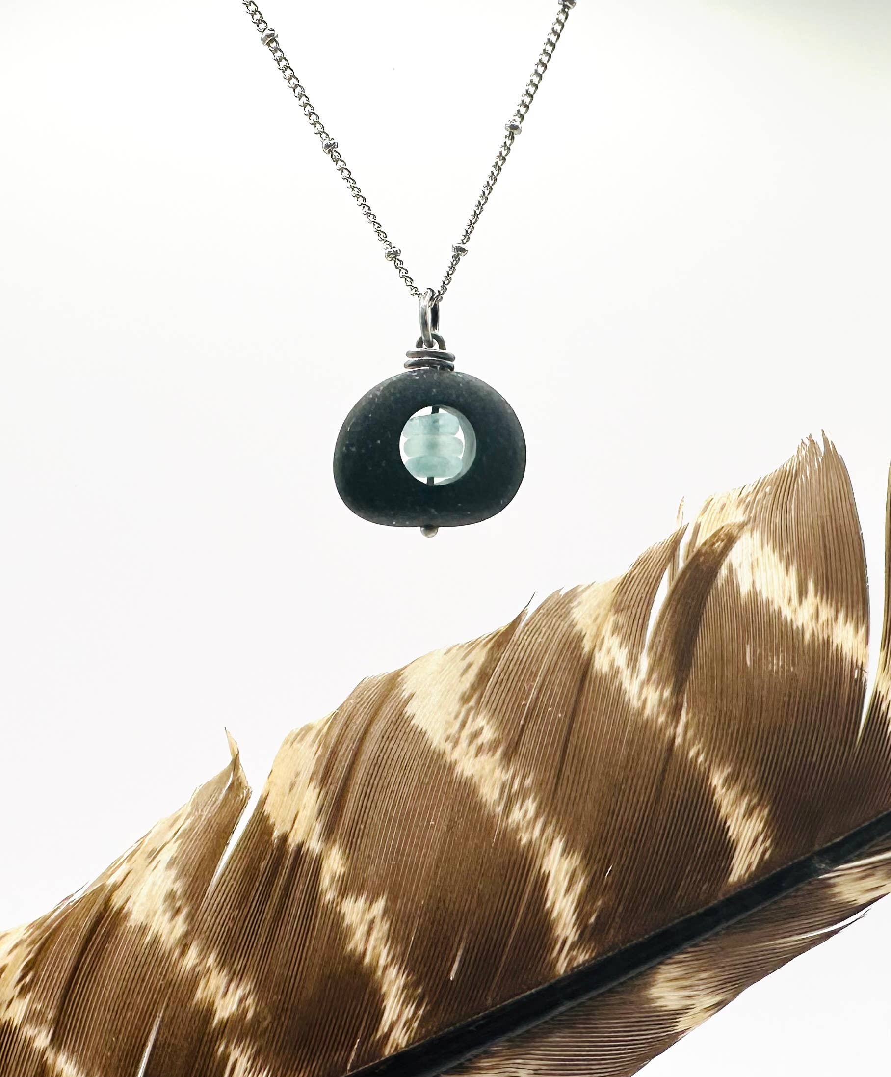 Black and Silver Ice Stack by Suzanna Garrett Designs — a river stone becomes the frame for a tiny stack of sea glass in this beautifully unexpected pendant