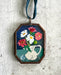 Vintage-style flowers in a vase pitcher art locket ornament.