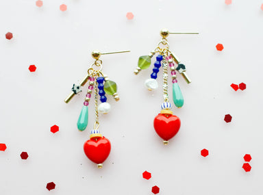Colorful Heart Charm Earrings by Jill Makes featuring a cluster of colorful beads and a heart pendant, displayed against a white background with red sequins.