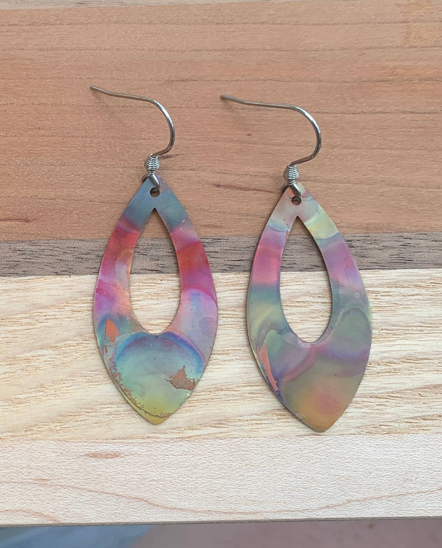 Pointed Teardrop Fire Painted Copper Earrings hanging from stainless steel ear wires showcasing vibrant colors.