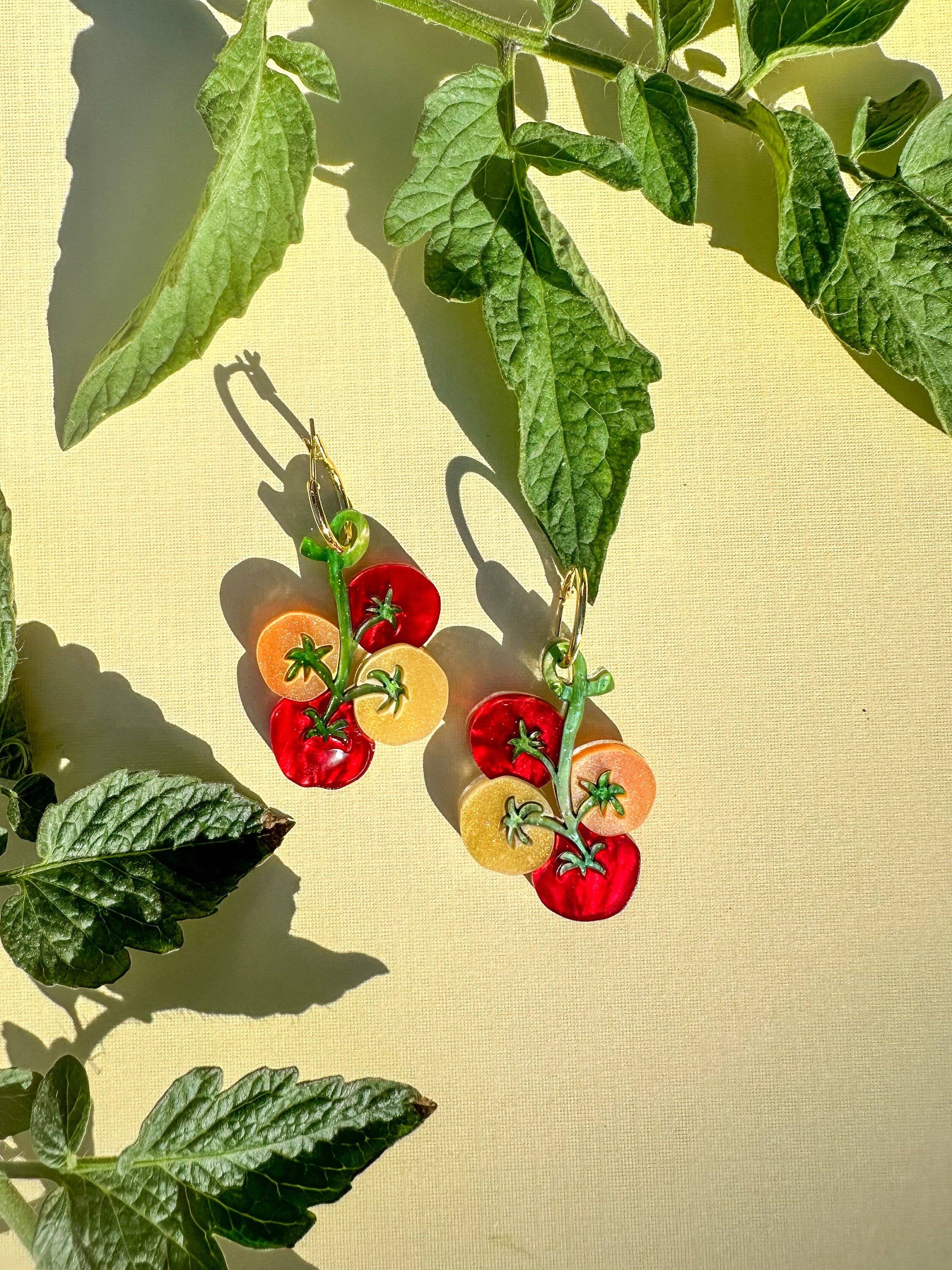 Handmade Cherry Tomato Dangle earrings by Sunnie Creative, showcasing a vibrant design featuring cherry tomatoes against a pastel yellow background, surrounded by fresh green leaves.