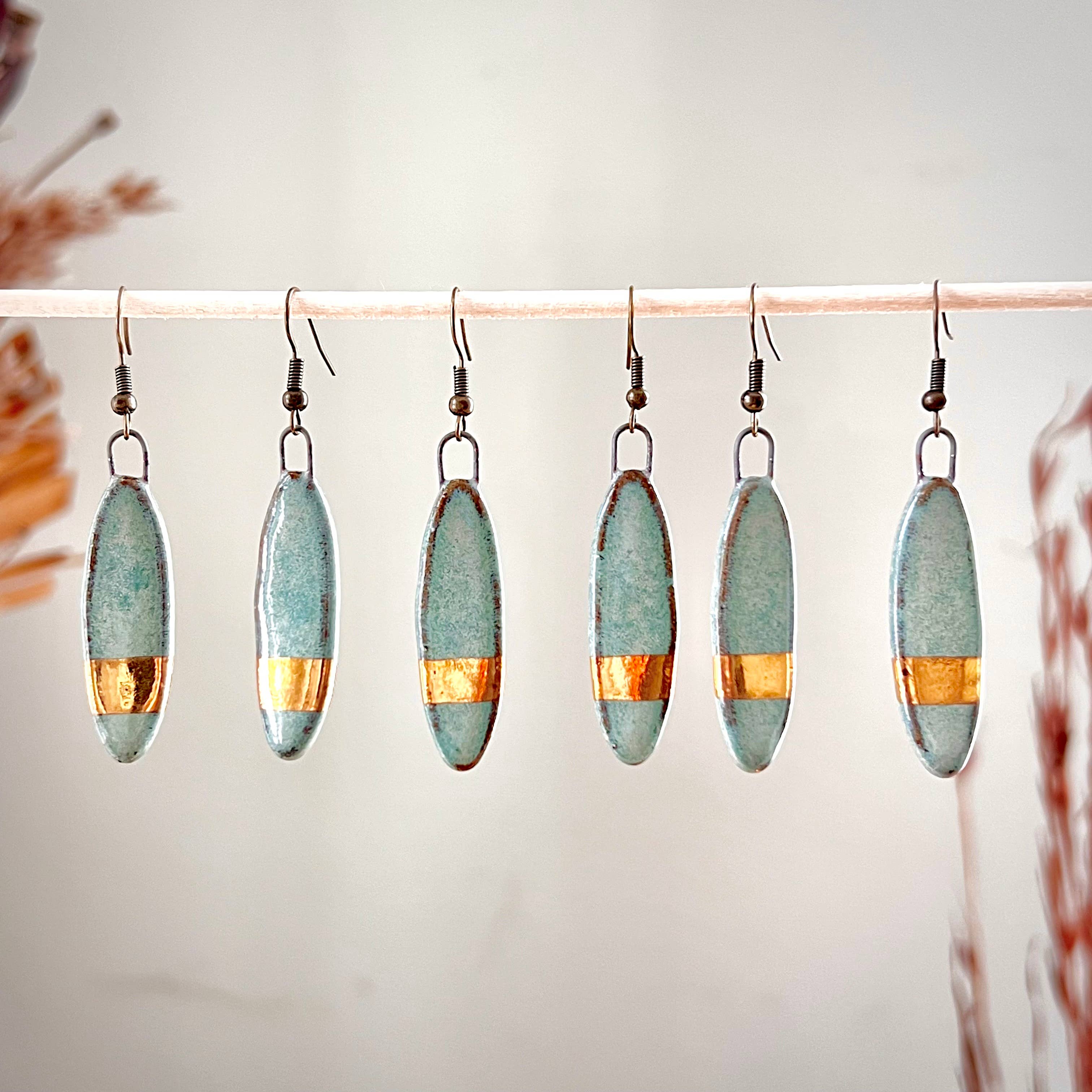 Elegant turquoise and solid gold striped earrings by The Artifact House, showcasing a handmade ceramic design with unique textures and colors.