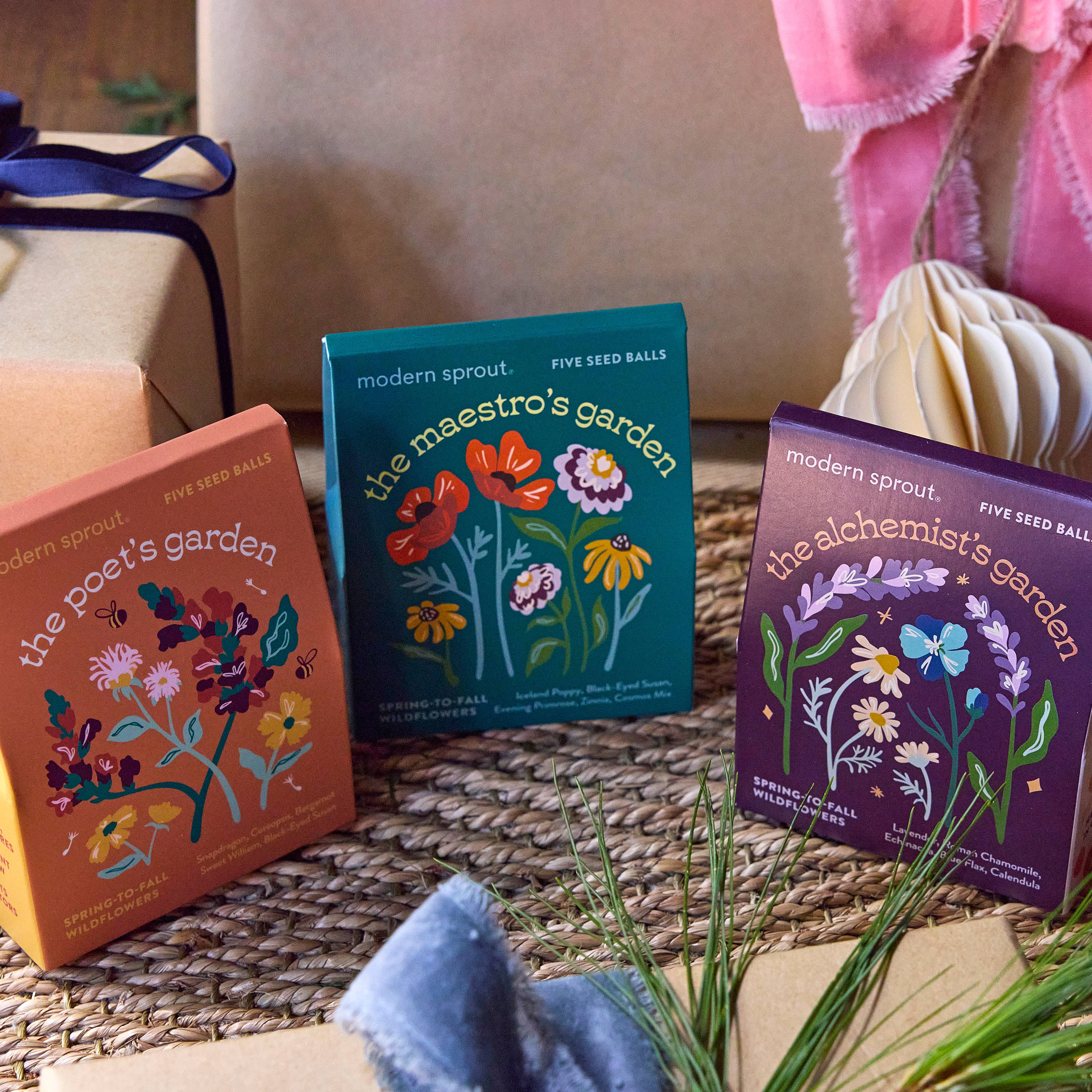 An artistic display of three different seed ball kits from Modern Sprout, showcasing 'The Poet's Garden,' 'The Maestro's Garden,' and 'The Alchemist's Garden.' Each kit contains a unique selection of vibrant flowers, embodying the essence of 'Bespoke Blooms' to inspire creative gardening experiences.