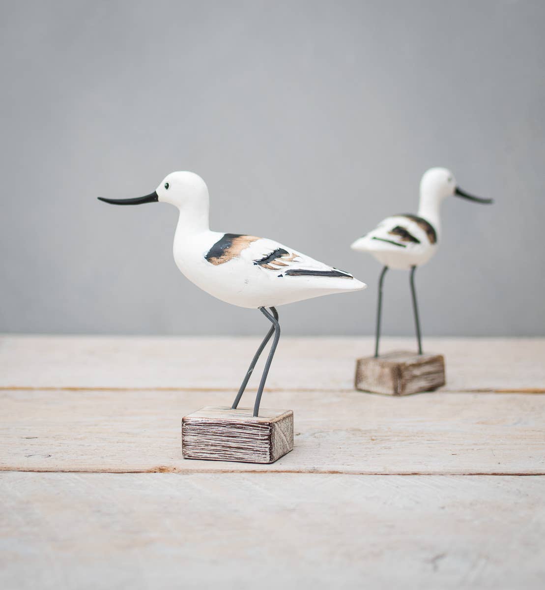 Mini Avocet figurine hand crafted by Aviologie, featuring a delicate shorebird design with intricate details and painted finish, displayed on a rustic wooden base.