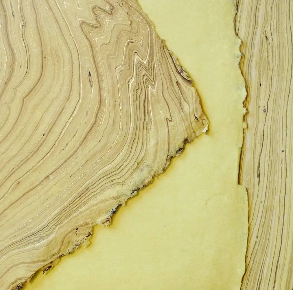 Detailed view of a hand marbled softcover notebook with yellow-toned marbled paper, created by The Casual Bookbinder.