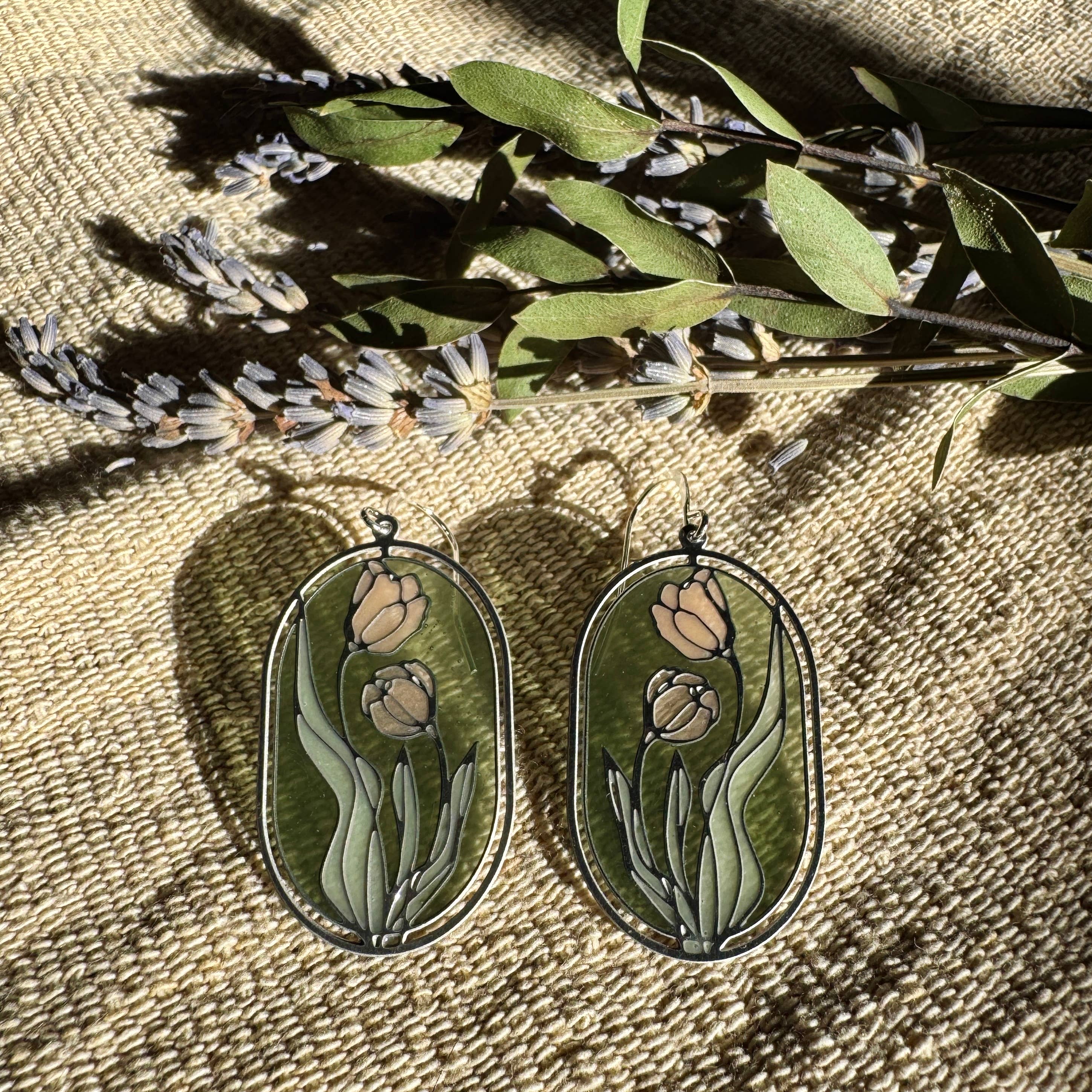 Camellias Stained Glass Resin Earrings by Wild Lupine Folkcraft, showcasing a stainless steel botanical design infused with soft-colored resin, beautifully catching the light against a natural background.