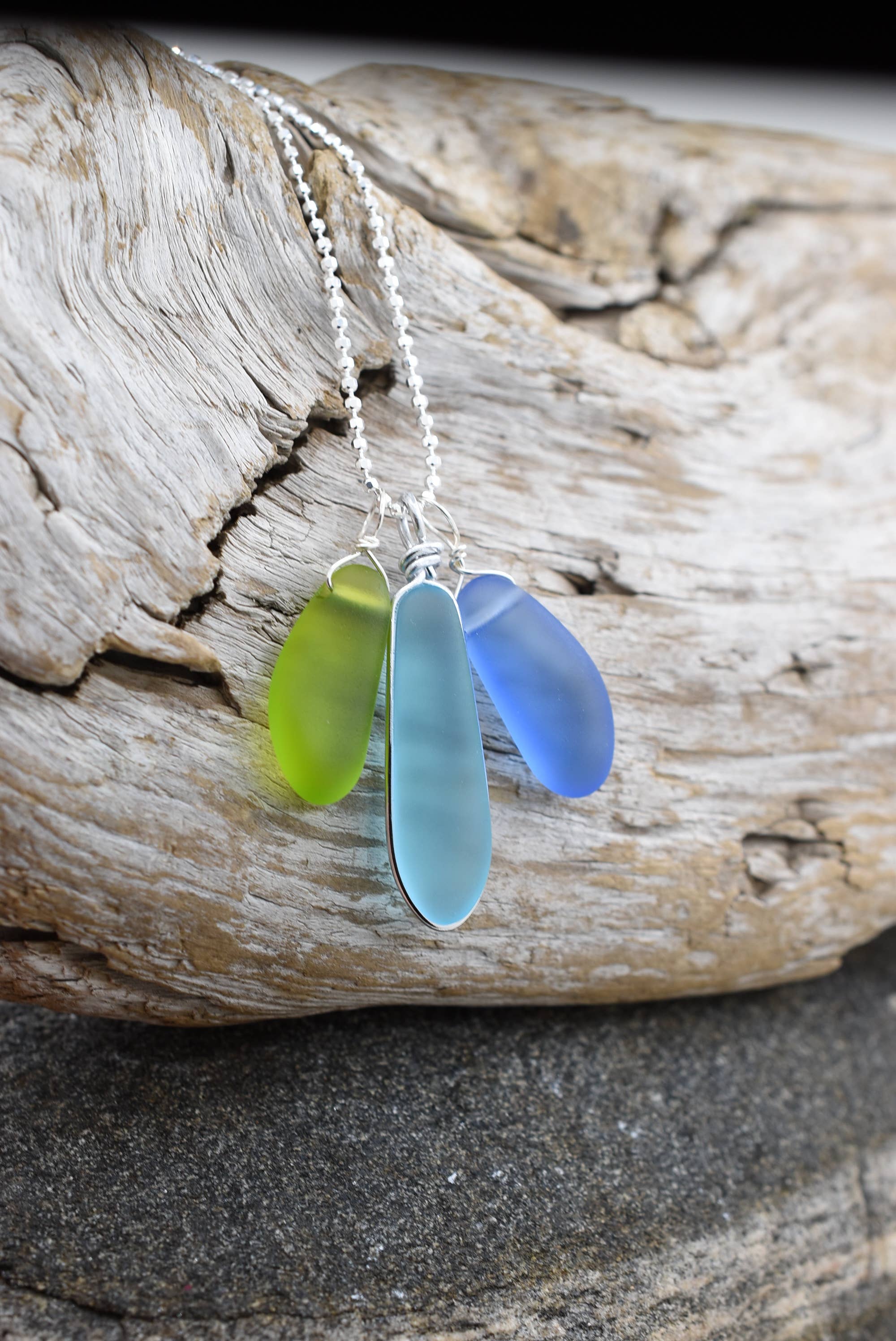 Close-up view of the Eco Glass Trio Sterling Silver Necklace showcasing the intricate wire-wrapping of recycled glass drops, highlighting its eco-friendly design.