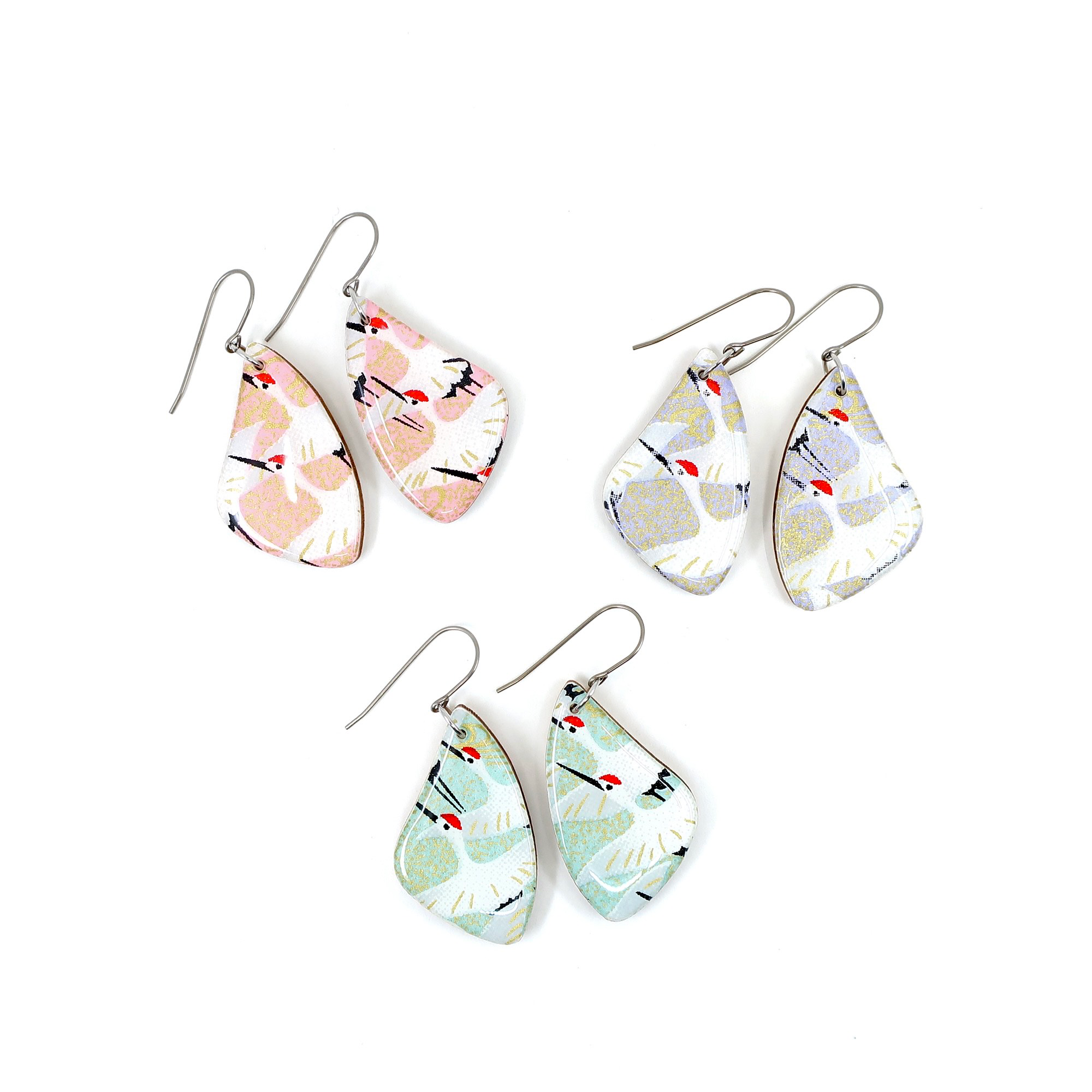 Close-up of green Crane Japanese titanium dangle earrings, showcasing the unique laser cut wood and stylish titanium wire hook.