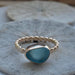 The Repetition Band | Sea Glass Ring by Kate Samson Design displaying a light aqua sea glass in a handcrafted bezel on a smooth textured gold band, set against a natural background.