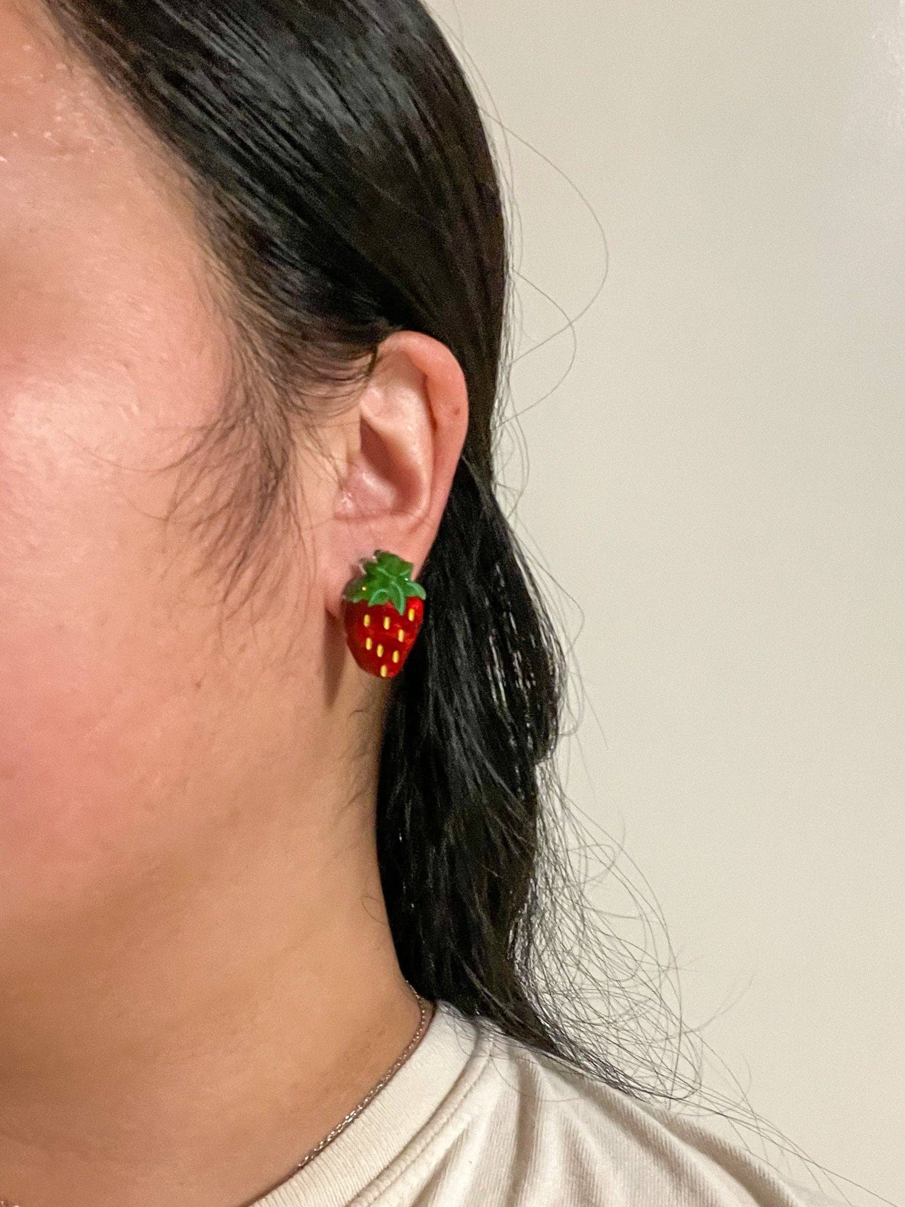 Side view of Mini Strawberry Acrylic Dangle Earrings by Sunnie Creative worn by an individual, showcasing the unique strawberry design.