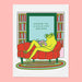 Cozy birthday card featuring a frog relaxing on a red couch with a book, accompanied by the text 'WISHING YOU A NICE & COZY BIRTHDAY', part of The Good Twin's 'The Good Twin Card Collection'.