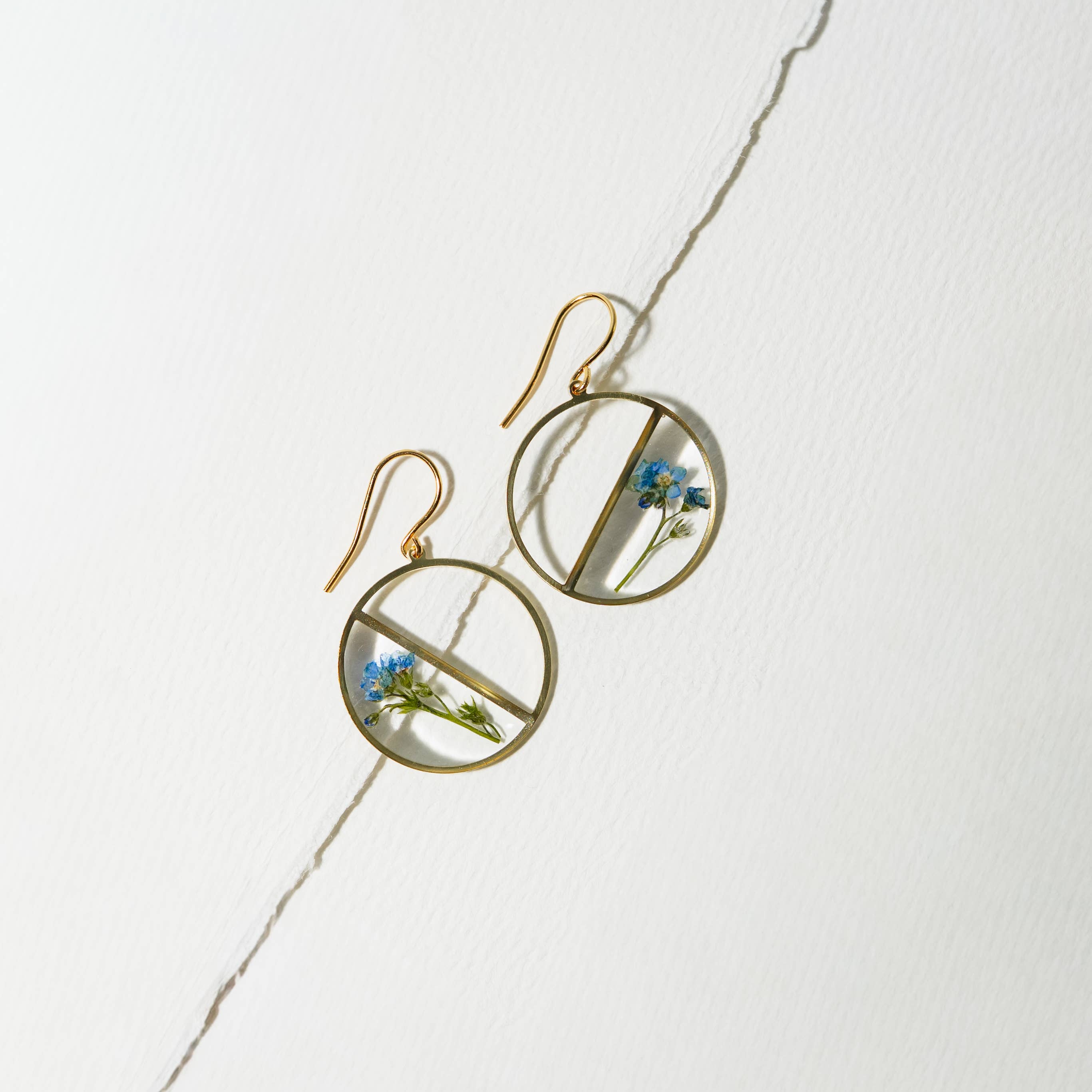 Close-up view of Forget Me Not Pressed Flower Earrings showcasing the intricate design with half circle filled with flowers and resin.