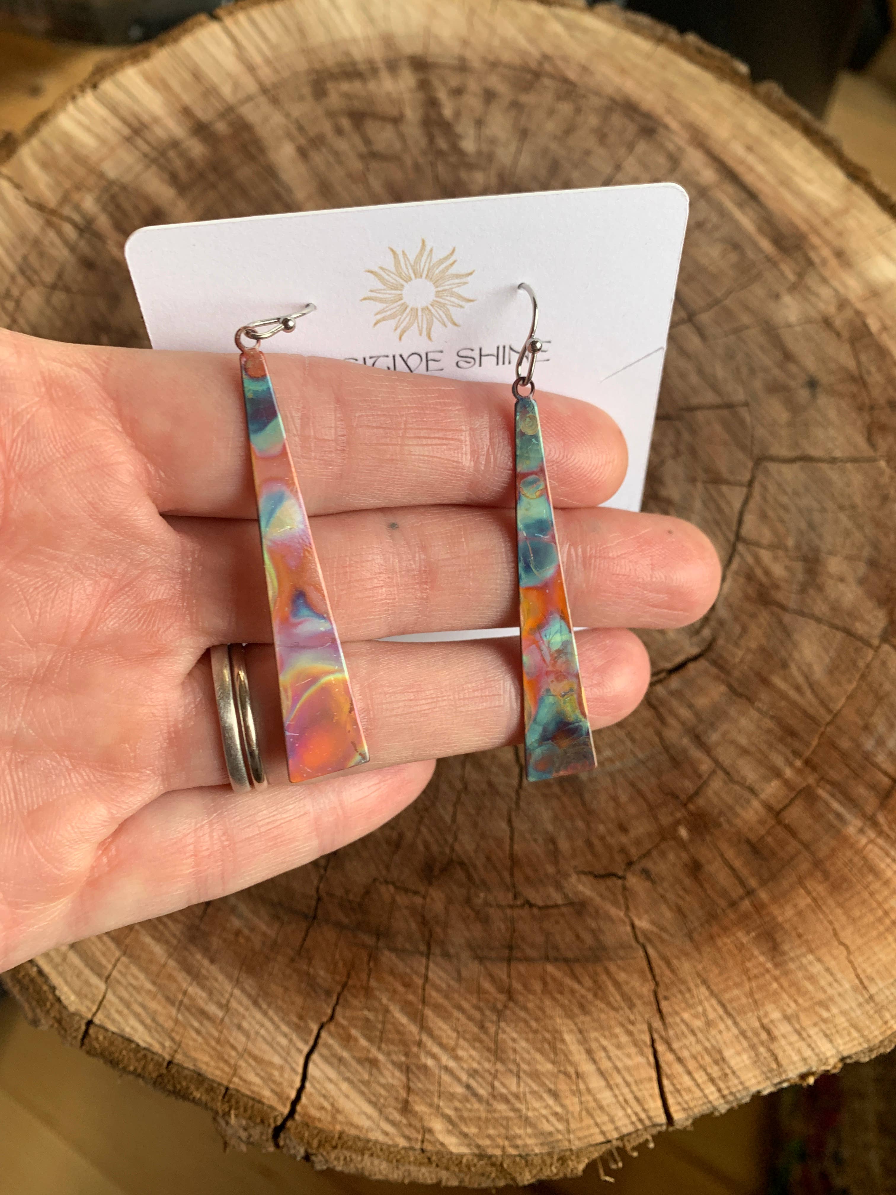 Triangle Stick Earrings hanging from stainless steel wires, emphasizing their elegant design with a protective coating.