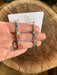 Triangle Stick Earrings hanging from stainless steel wires, emphasizing their elegant design with a protective coating.