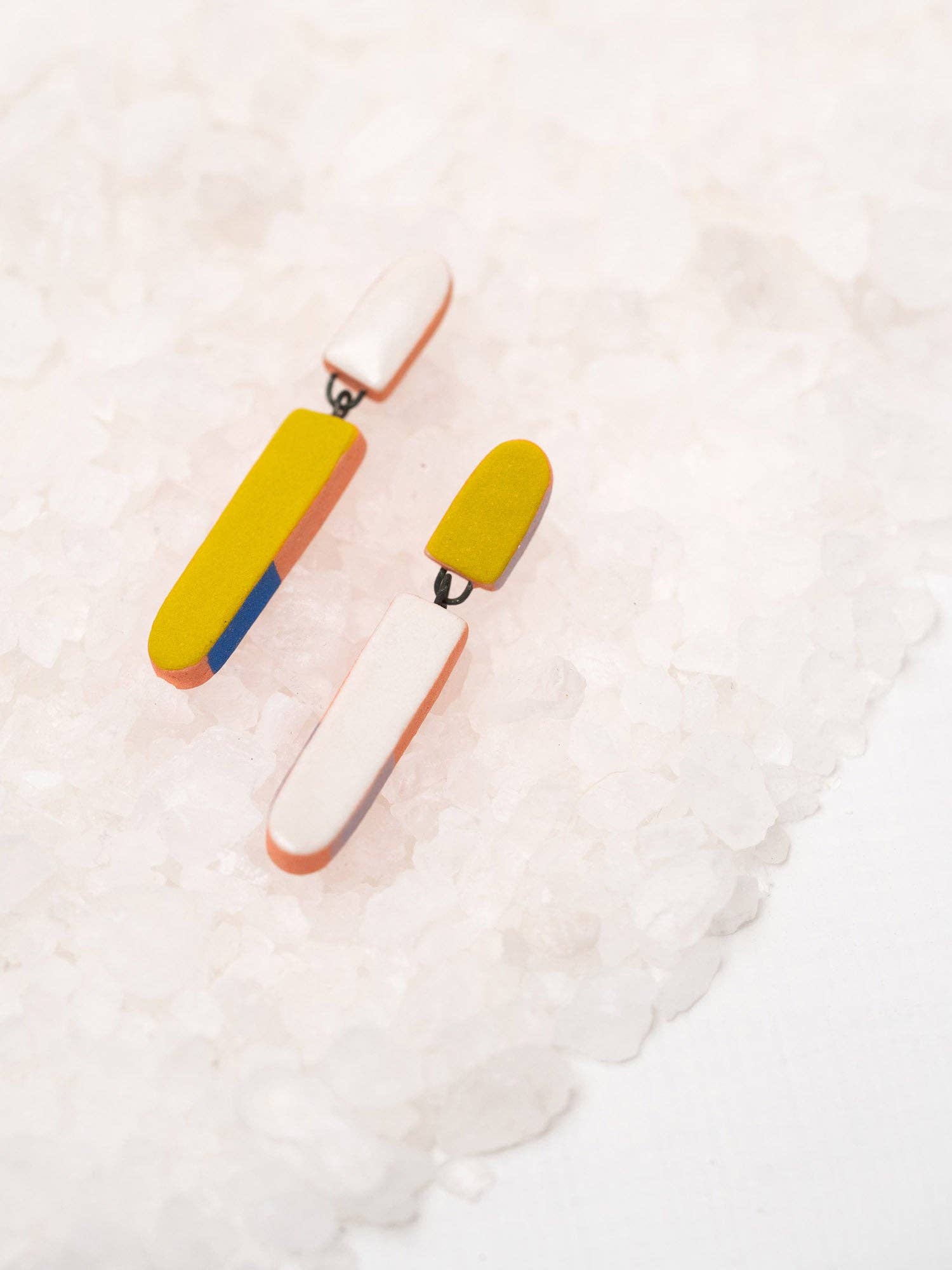 Colorful Split Dip Earrings by Twenty Two West displayed on a textured salt background, featuring a playful design with bold colors and a porcelain finish.