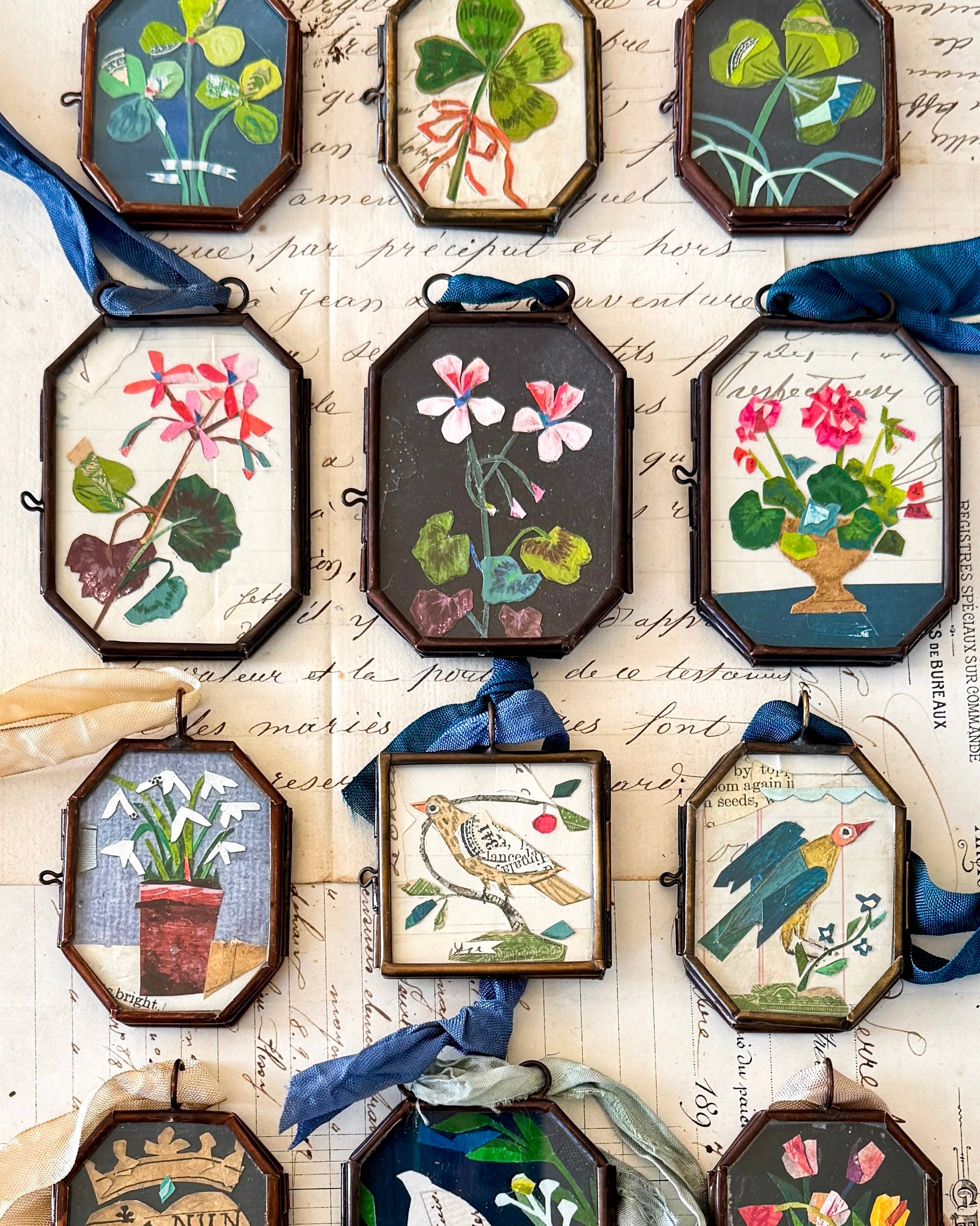A collection of handcrafted art lockets featuring vibrant floral and bird illustrations, designed by Maris Mirum. The locket ornaments showcase the unique collage style of Brandie Stonge, perfect for home decor and seasonal gifts, titled 'Cerise Folk Bird'.