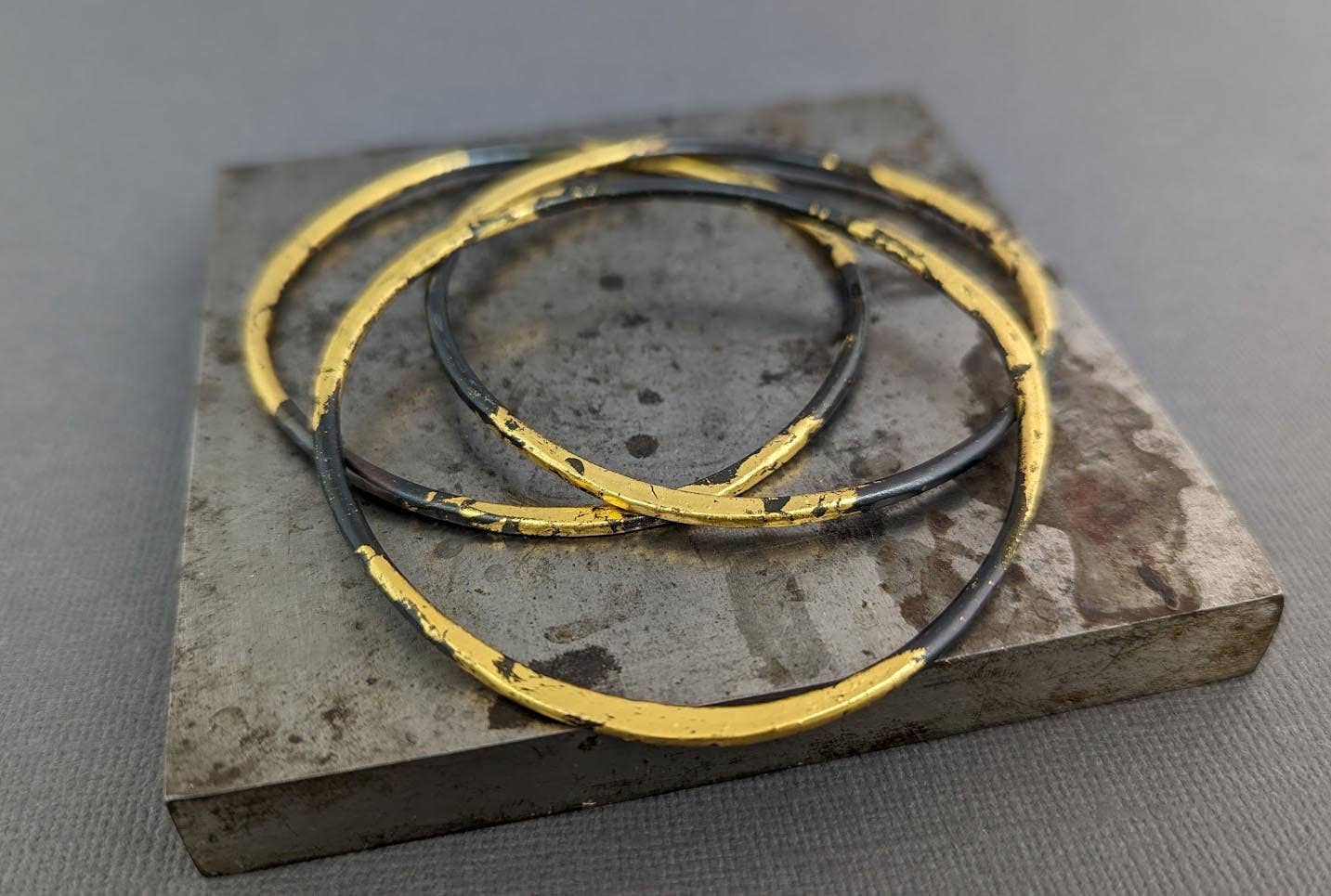 A stunning Forged Steel and Gold Bangle, perfect for those who want to feel like royalty without the risk of being chased by dragons! Crafted from heavy 10 gauge steel and elegantly gilded in 23k gold, this unique bangle adds a touch of regality to any outfit.