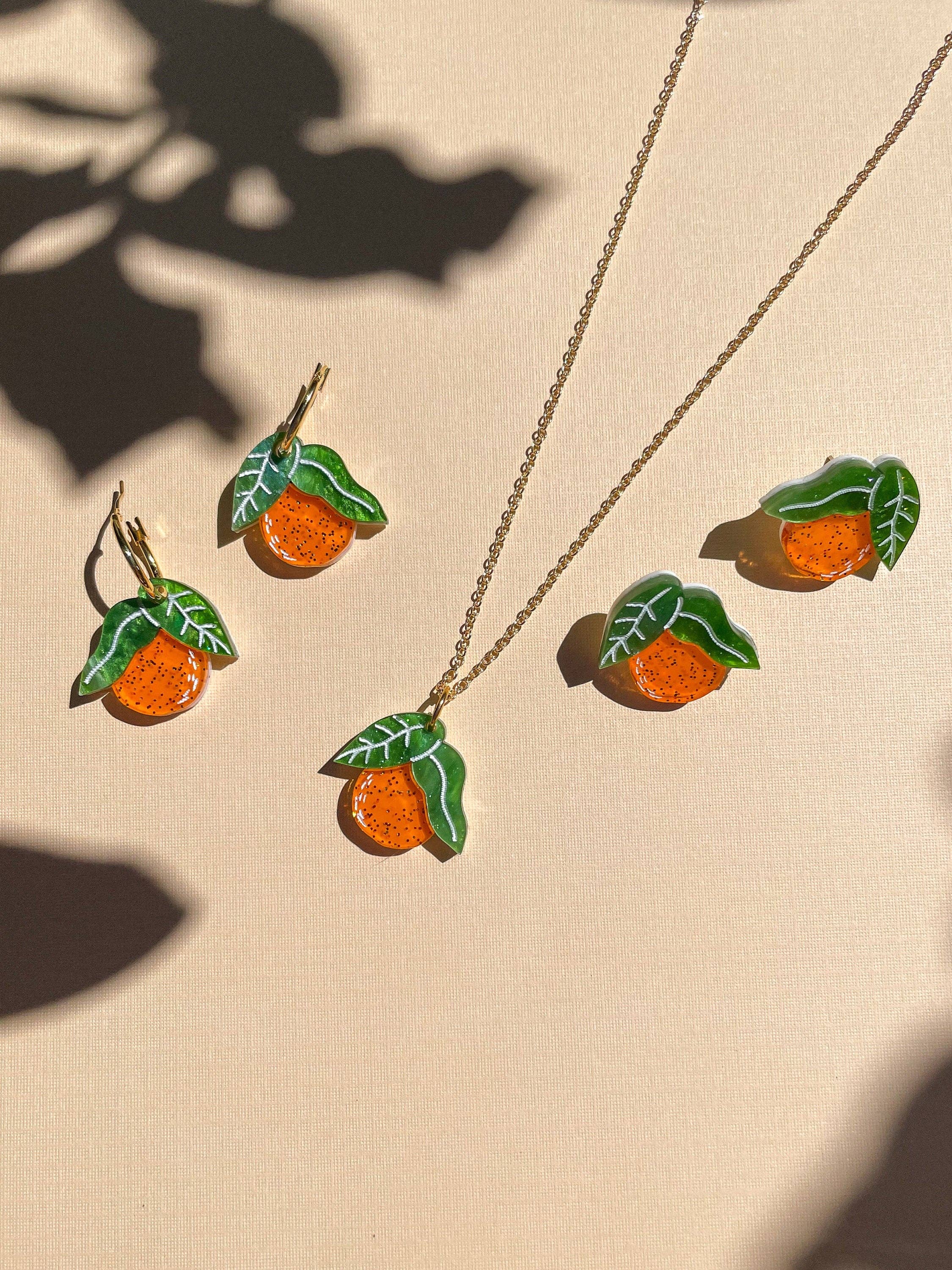 Mini Orange Necklace and matching earrings by Sunnie Creative, displaying a playful orange theme with leaf accents, highlighting the artisan craftsmanship on a gentle backdrop.