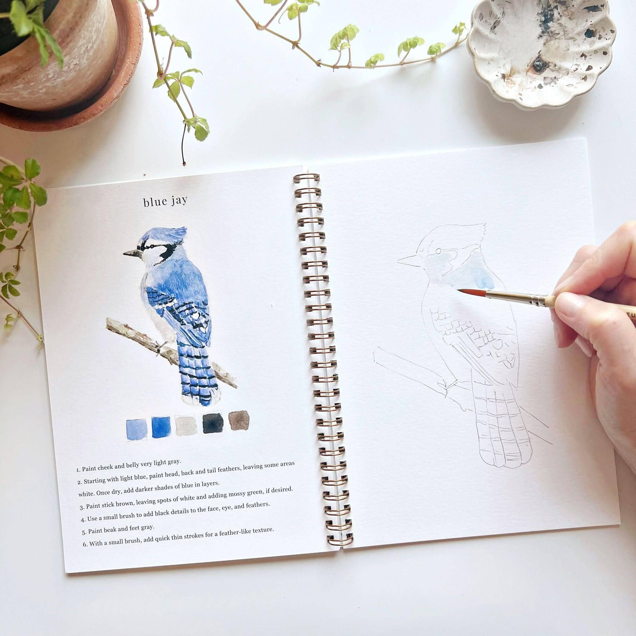 A user painting in the Birds Watercolor Workbook with watercolors, illustrating the fun and relaxing nature of the activity.