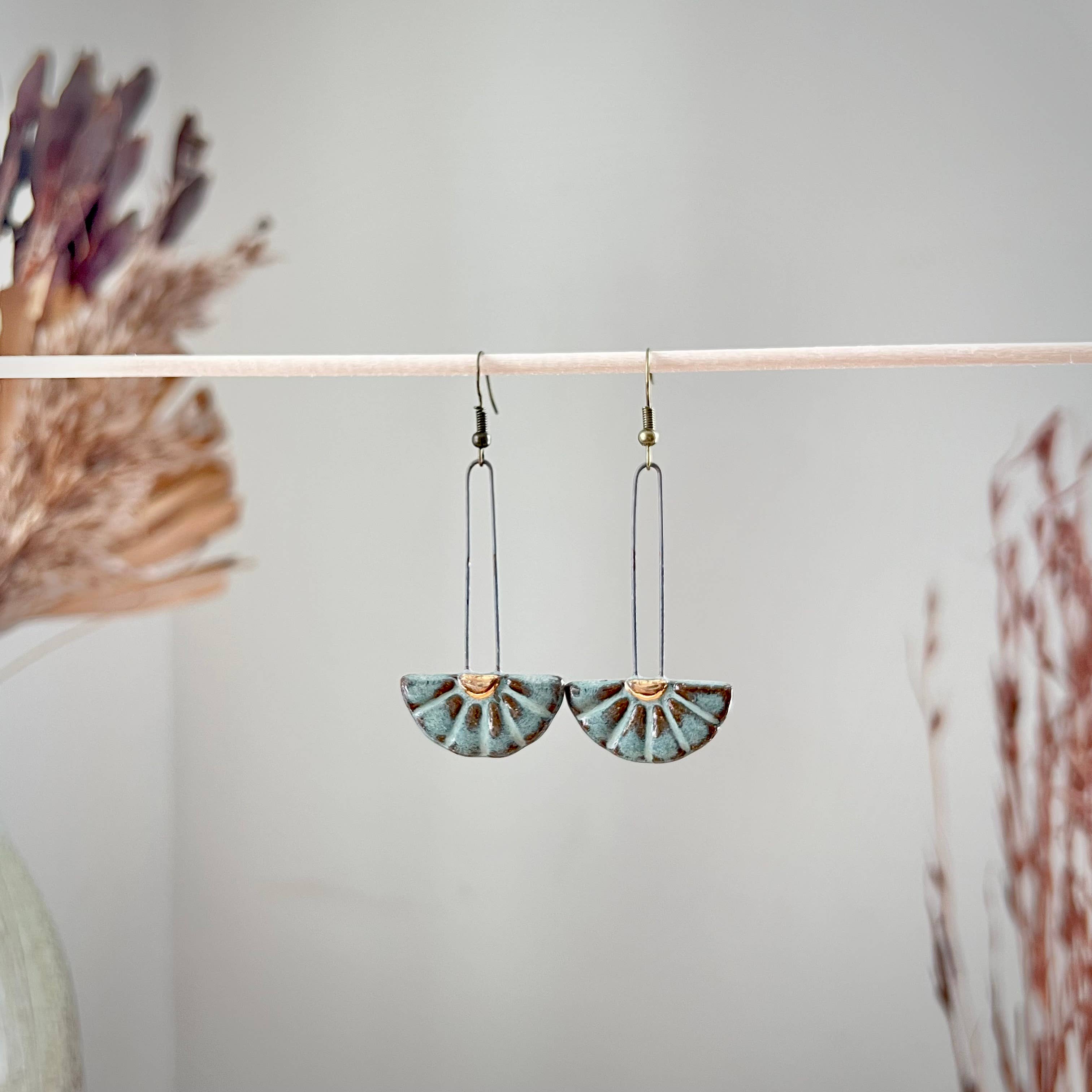 Turquoise Sun Burst Ceramic Earrings by The Artifact House captured in a close-up, emphasizing their radiant glaze and distinctive sun burst pattern.