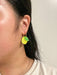 A person wearing Mini Lemon Dangle earrings, highlighting the unique yellow acrylic design with green leaf accents made by Sunnie Creative.