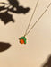 Mini Orange Necklace by Sunnie Creative, featuring a vibrant orange pendant with green leaves, resting on a soft background, showcasing the unique handmade design.