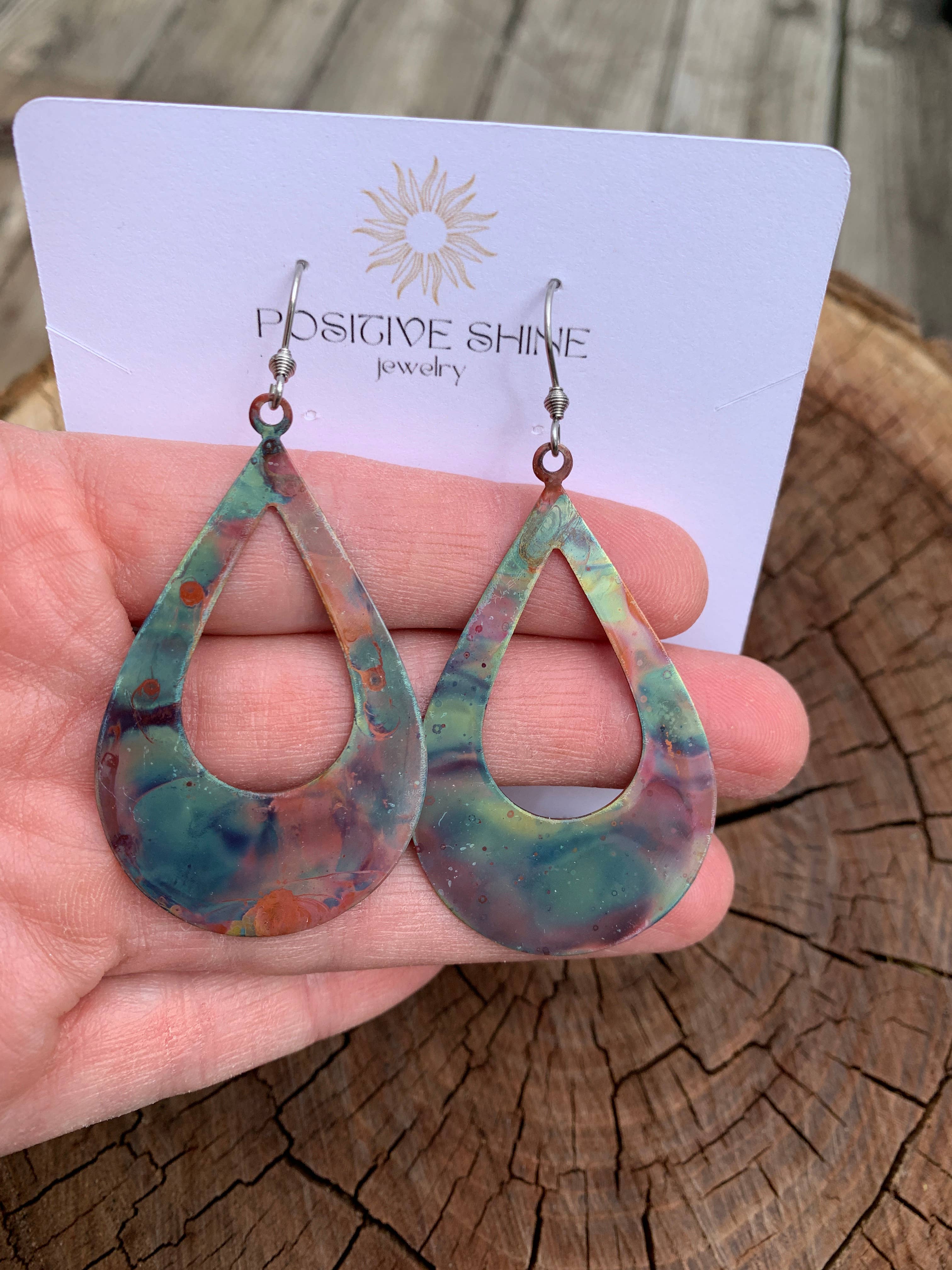 Boho Large Open Teardrop Fire Painted Copper Earrings hanging elegantly, showcasing vibrant colors and unique patterns.