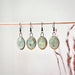Multiple pairs of Turquoise Oval Earrings with Gold Checkered Lines hanging on a display, showcasing the elegant design by The Artifact House.
