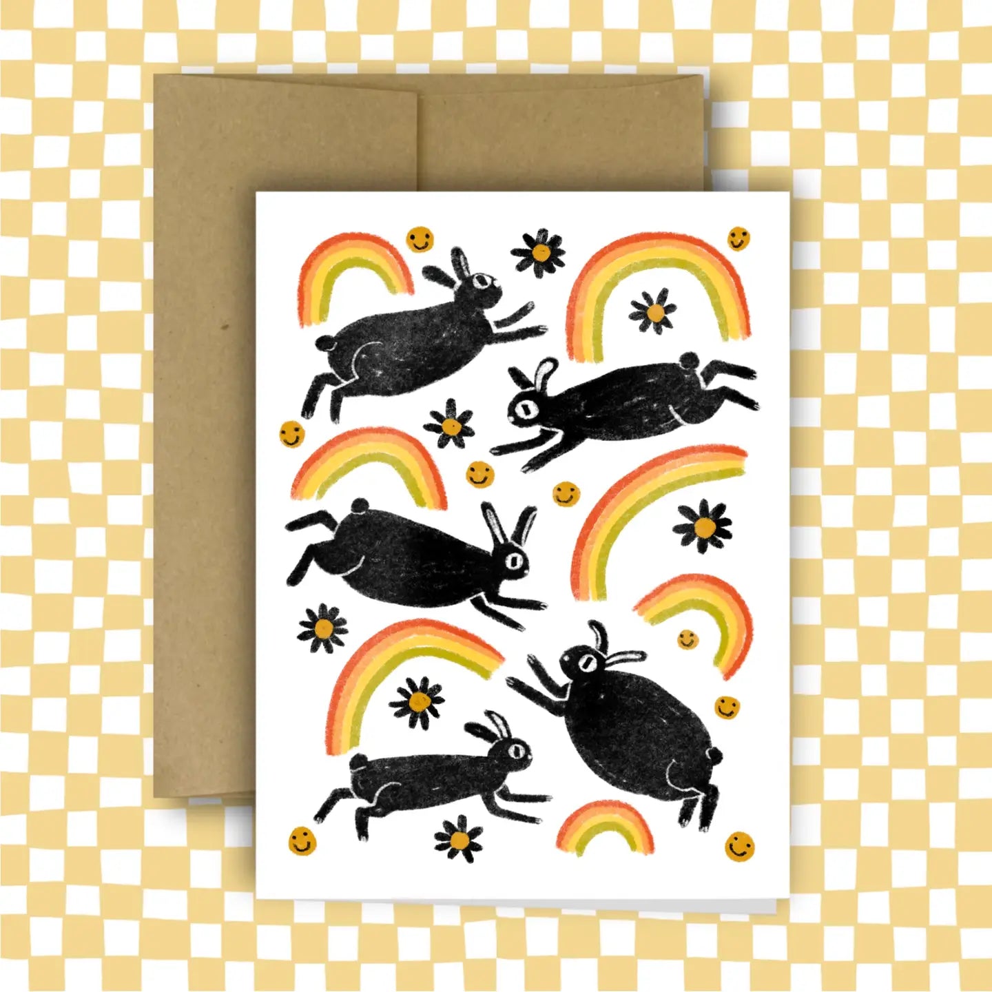 Greeting card with black rabbit illustrations and rainbows on a white background, with a brown envelope.
